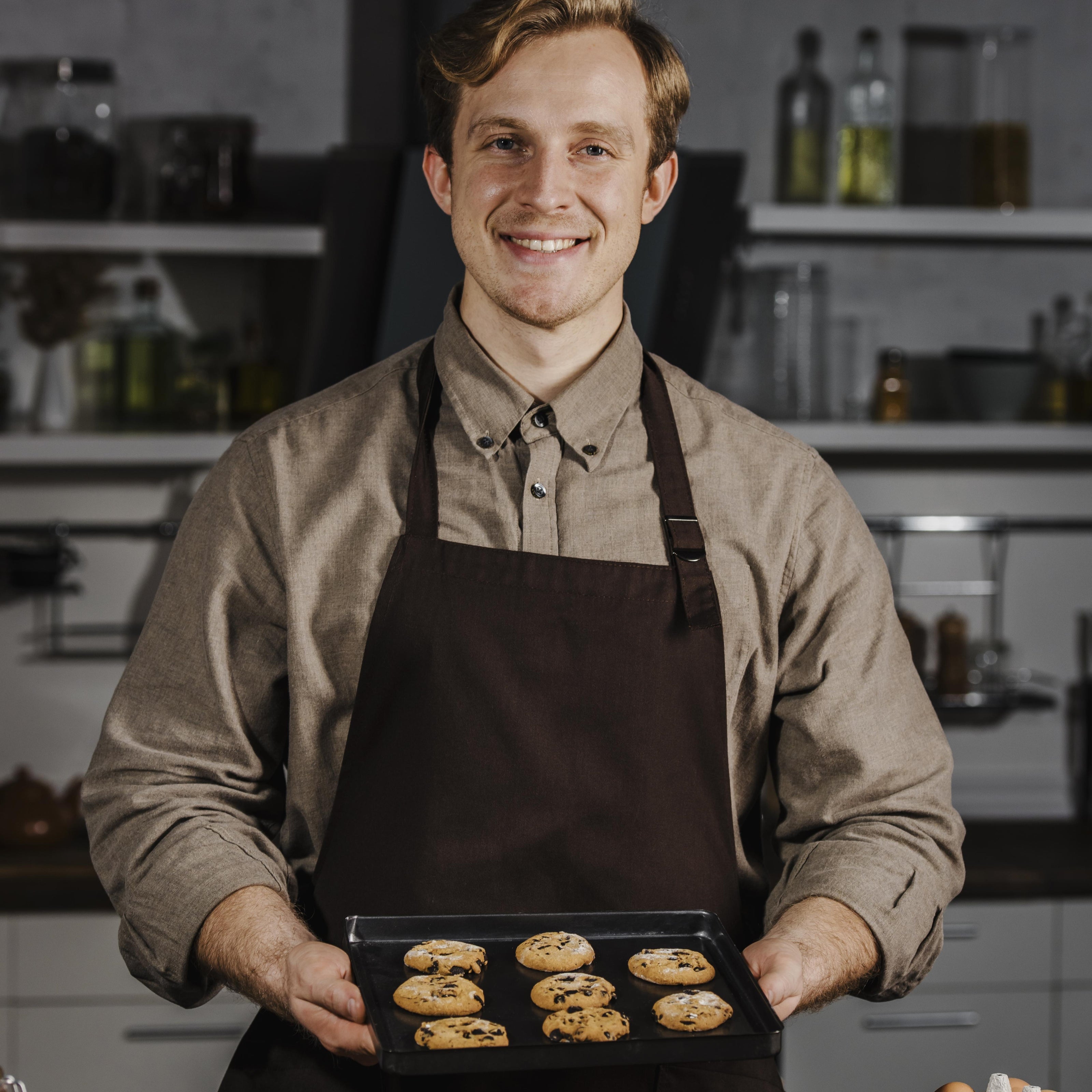 Smiling chef holding a tray of cookies.