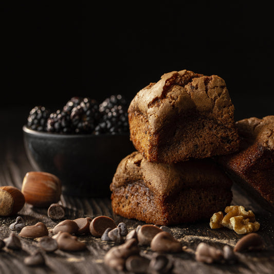 Front close-up view of several brioche bites with nuts and blackberries used as decor.